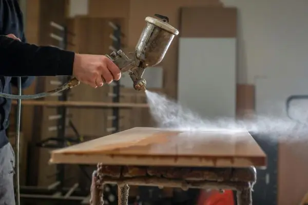 worker spraying wood 