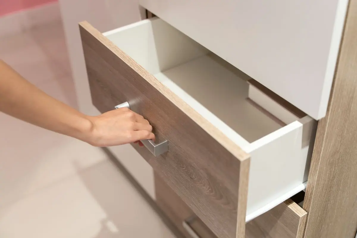 woman open shelf, pull open drawer wooden in cabinet