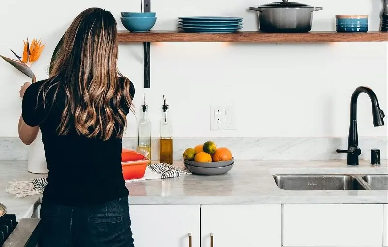 woman cleaning kitchen with custom cabinets on the wall