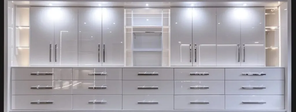 a sleek and modern built-in wardrobe with glossy white doors and elegant chrome handles, perfectly organized with shelf and drawers